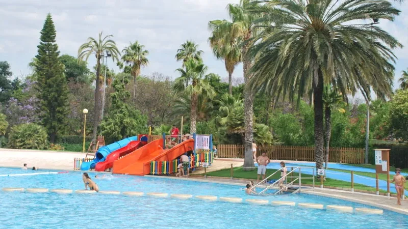 Piscina de Benicalap en Valencia con toboganes y zonas verdes, ideal para disfrutar del verano en familia Piscina del Parque de Benicalap en Valencia con toboganes y palmeras, una de las mejores opciones para verano.