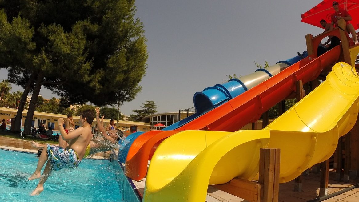 Piscina del Parque del Oeste en Valencia con toboganes para niños, una de las mejores piscinas para verano Niños lanzándose por los toboganes de la piscina del Parque del Oeste en Valencia durante el verano.